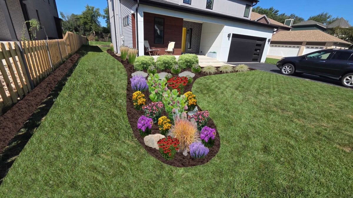 A garden bed with colorful flowers and plants is bordered by mulch in the front lawn of a modern house, with a car parked in the driveway and wooden fencing along the yard.