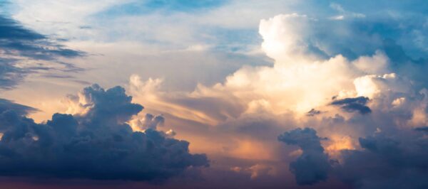 Colorful sky with dramatic clouds at sunset; deep blue and purple clouds contrast with golden and orange light illuminating the sky.