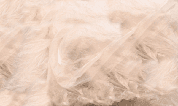 Close-up of crumpled, semi-transparent plastic bags with a soft beige tint, creating an abstract, textured pattern.