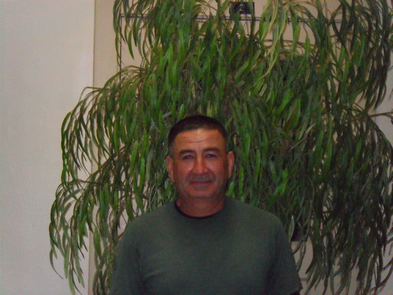 Gaspar S. A man with short dark hair and a green shirt stands in front of a tall leafy plant indoors, smiling slightly at the camera.