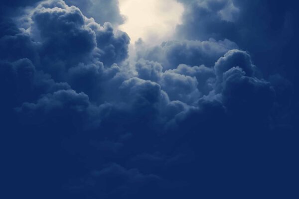 Dark, dense storm clouds fill the sky, with a bright patch of light breaking through at the top center, creating a dramatic and moody atmosphere.