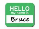 A green name tag with the text HELLO my name is in white letters and Bruce handwritten in black below.