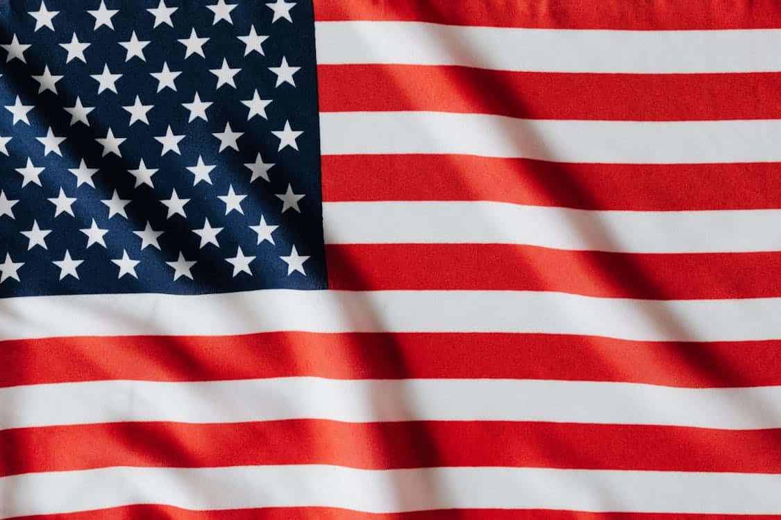 Close-up of the United States flag showing stars on a blue field and red and white stripes, with visible fabric folds.