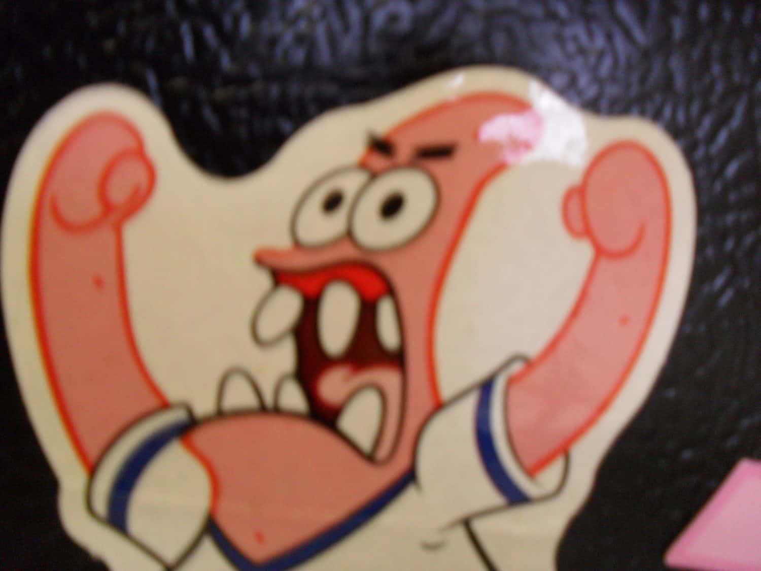 Tom - President A cartoon character with pink skin, raised arms, wide open mouth, and exaggerated teeth and eyes, appearing to shout or scream with an intense expression.